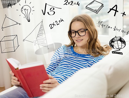 Image of smiling teenage girl reading book on couch