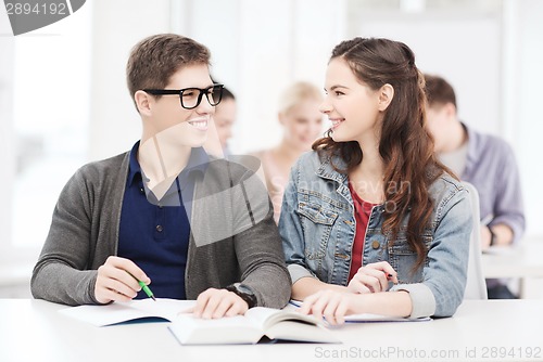 Image of two teenagers with notebooks and book at school