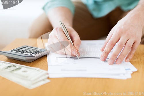 Image of close up of man counting money and making notes