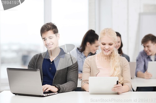 Image of two smiling students with laptop and tablet pc