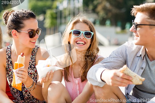 Image of group of smiling friends sitting on city square