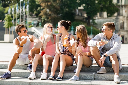 Image of group of smiling friends sitting on city square