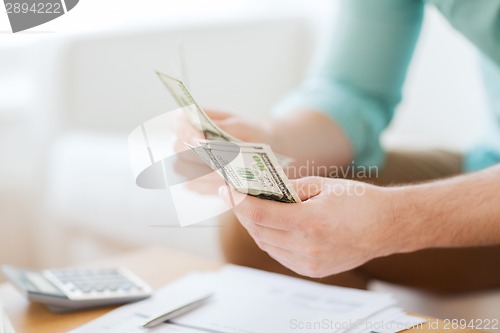 Image of close up of man counting money and making notes