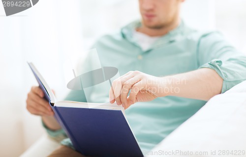 Image of close up of man reading book at home