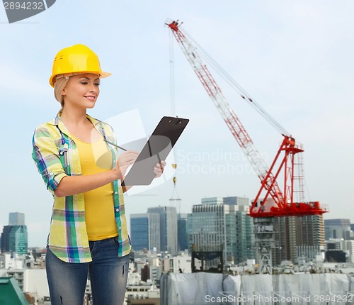 Image of smiling woman in helmet with clipboard