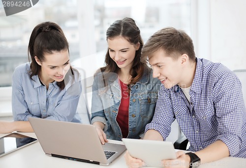 Image of three smiling students with laptop and tablet pc