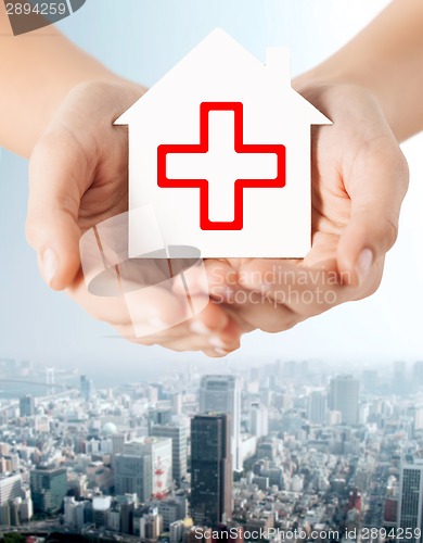 Image of hands holding paper house with red cross