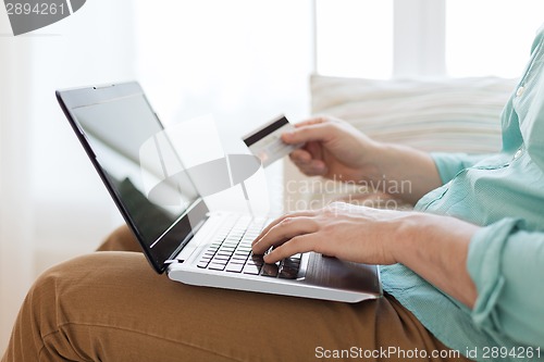 Image of close up of man with laptop and credit card