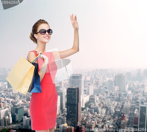 Image of smiling elegant woman in dress with shopping bags