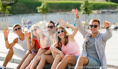 Image of group of laughing friends sitting on city square