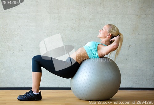 Image of smiling woman with exercise ball in gym