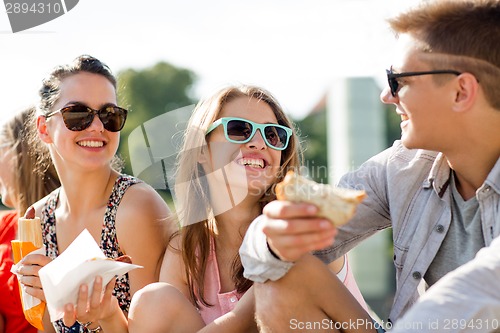 Image of group of smiling friends sitting on city square