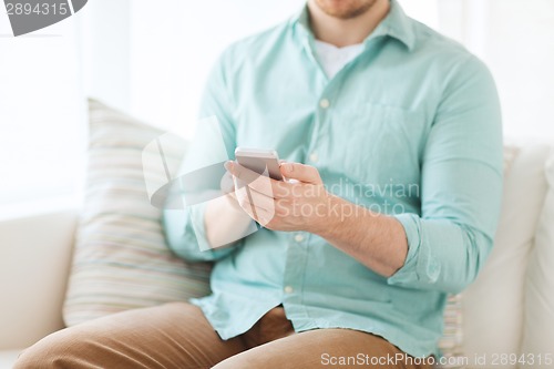 Image of close up of man sitting with smartphone at home