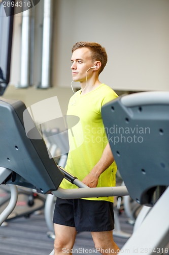 Image of man with smartphone exercising on treadmill in gym