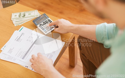 Image of close up of man counting money and making notes