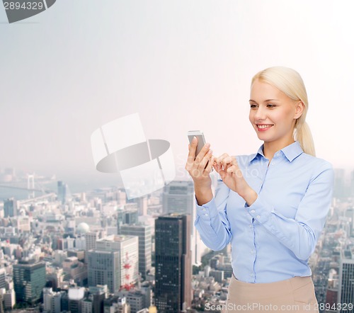 Image of young smiling businesswoman with smartphone