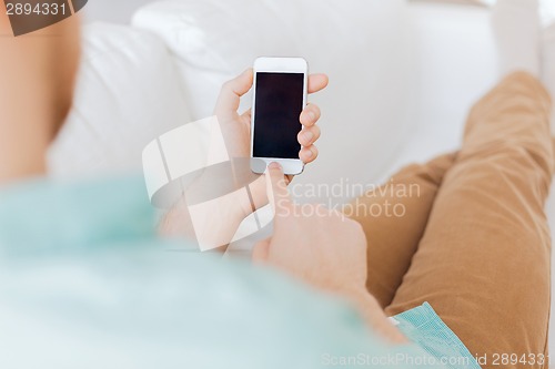 Image of close up of man sitting with smartphone at home