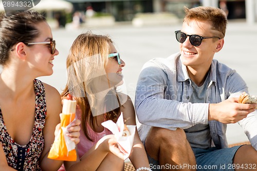 Image of group of smiling friends sitting on city square