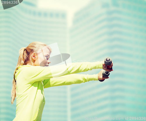 Image of sporty woman with light dumbbells outdoors