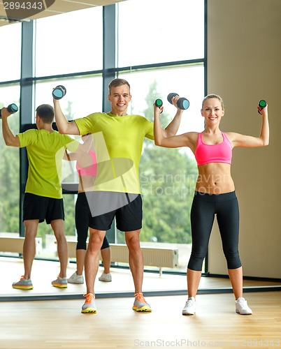 Image of smiling man and woman with dumbbells in gym