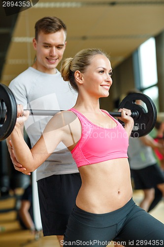 Image of smiling man and woman with barbell in gym