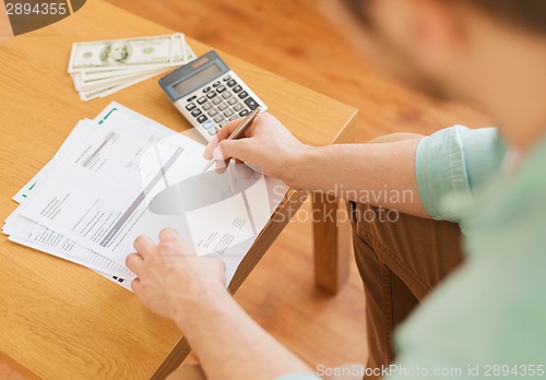 Image of close up of man counting money and making notes