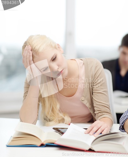 Image of tired teenage student with tablet pc and books