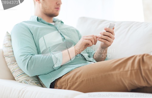 Image of close up of man sitting with smartphone at home