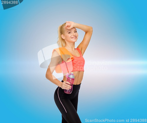 Image of smiling sporty woman with towel and water bottle