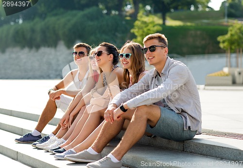 Image of group of smiling friends sitting on city square