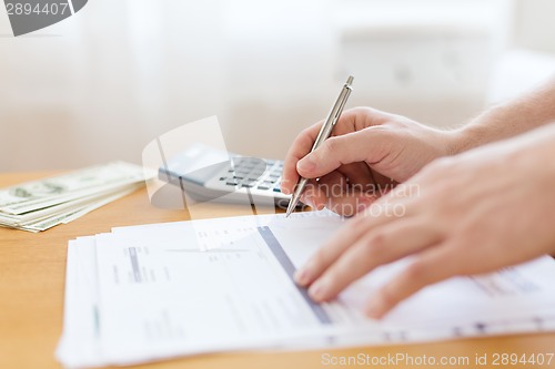 Image of close up of man counting money and making notes