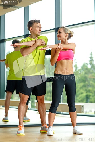 Image of smiling man and woman exercising in gym