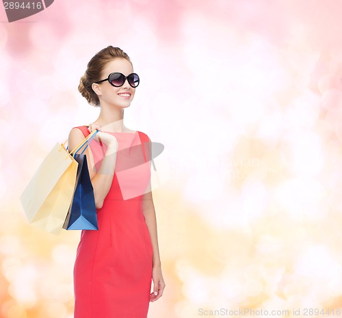 Image of smiling elegant woman in dress with shopping bags