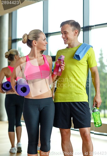 Image of smiling couple with water bottles in gym