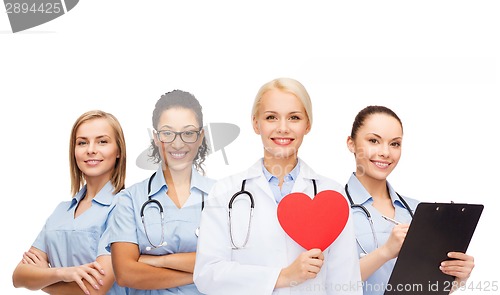 Image of smiling female doctor and nurses with red heart