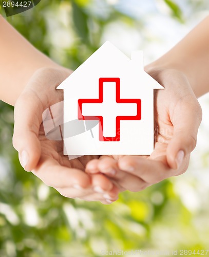 Image of hands holding paper house with red cross