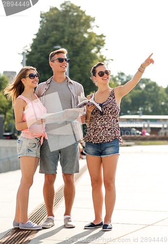 Image of smiling friends with map and city guide outdoors