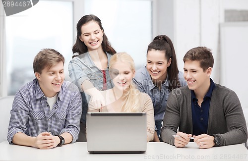 Image of smiling students looking at laptop at school