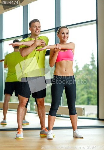 Image of smiling man and woman exercising in gym