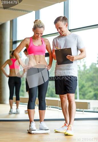 Image of smiling man and woman with scales in gym