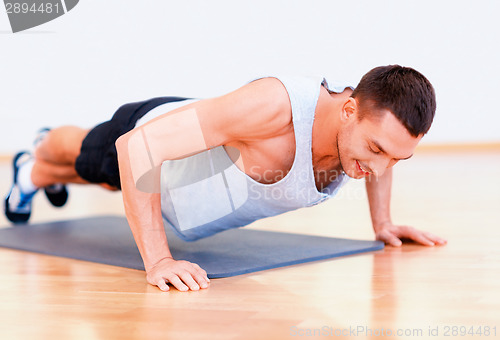 Image of smiling man doing push-ups in the gym