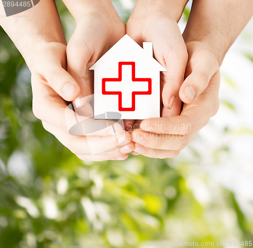 Image of hands holding paper house with red cross