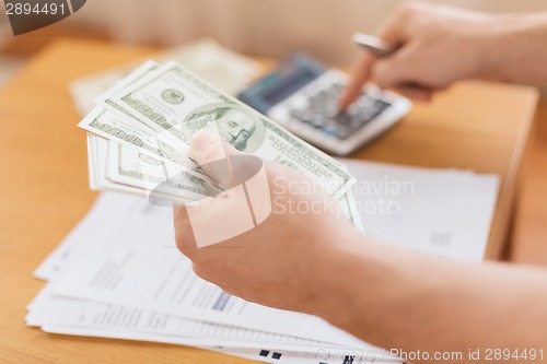 Image of close up of man counting money and making notes