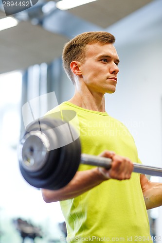 Image of man doing exercise with barbell in gym