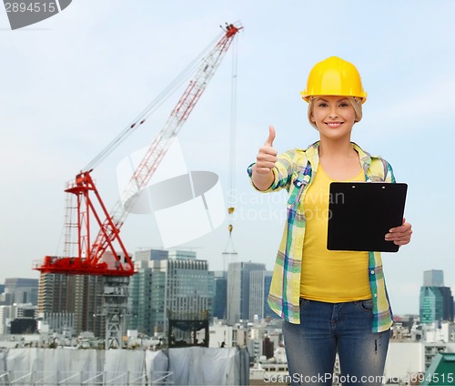 Image of smiling woman in helmet with clipboard