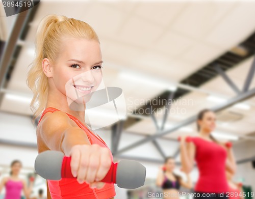 Image of smiling beautiful sporty woman with dumbbell