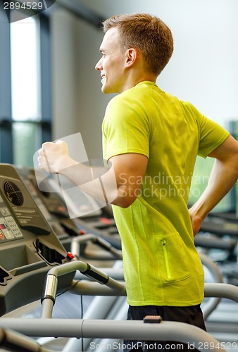 Image of smiling man exercising on treadmill in gym