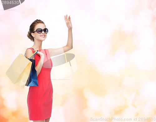 Image of smiling elegant woman in dress with shopping bags