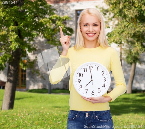 Image of student with wall clock and finger up