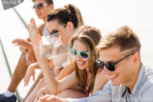 Image of group of laughing friends sitting on city square